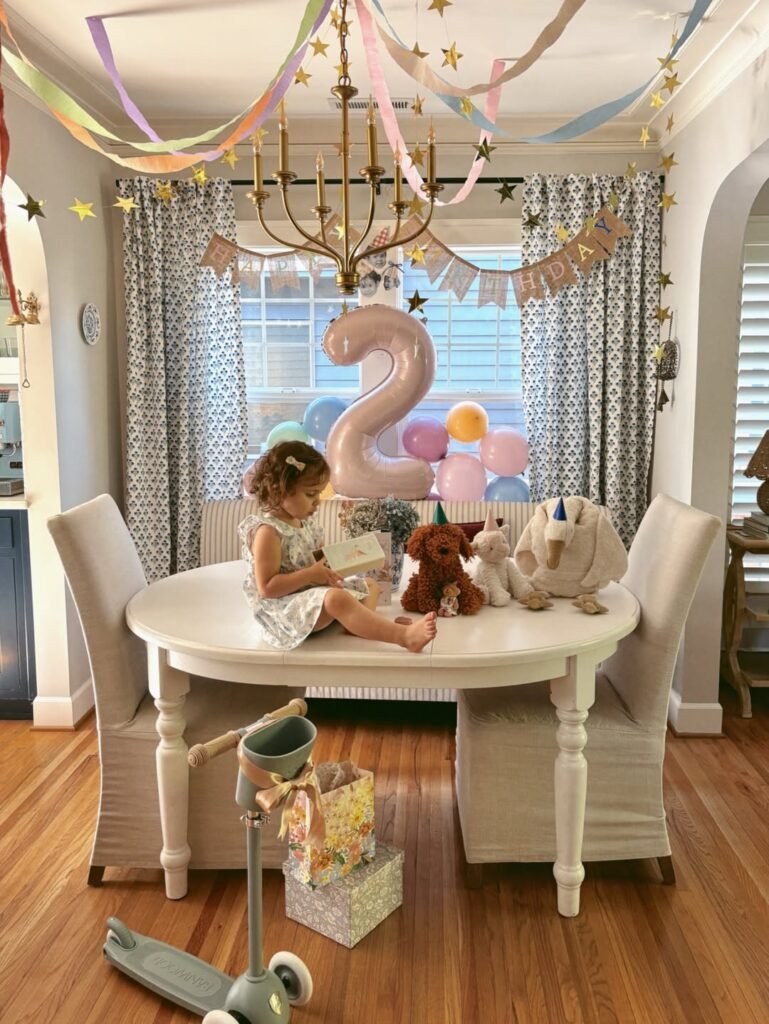 Birthday girl on the table under pastel streamers and gold stars