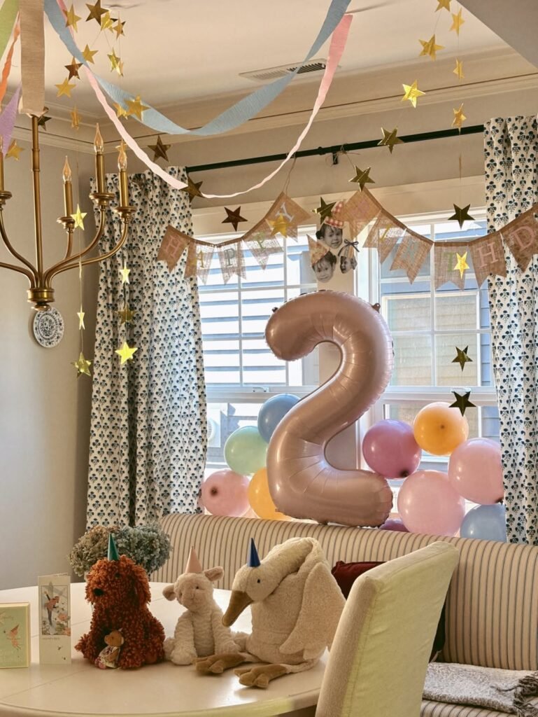 Dining room with a pink number 2 balloon, gold stars and plush animals on the table