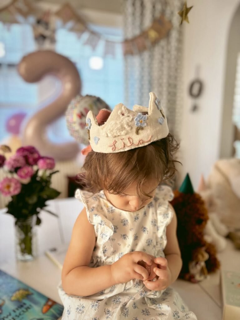 Birthday girl in a gold paper crown by a number 2 balloon