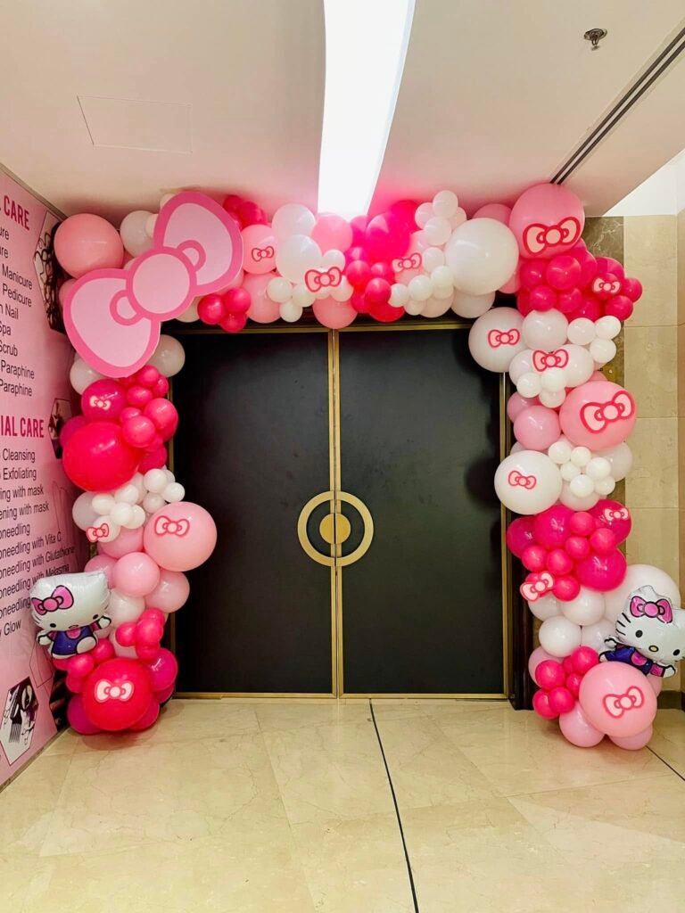Pink, red and white balloon arch with Hello Kitty balloons around a ballroom entrance door