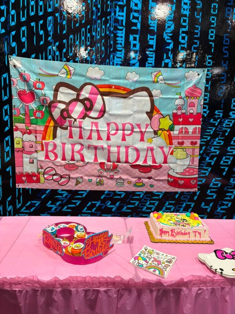 Hello Kitty Happy Birthday banner behind a pink cake table with treats