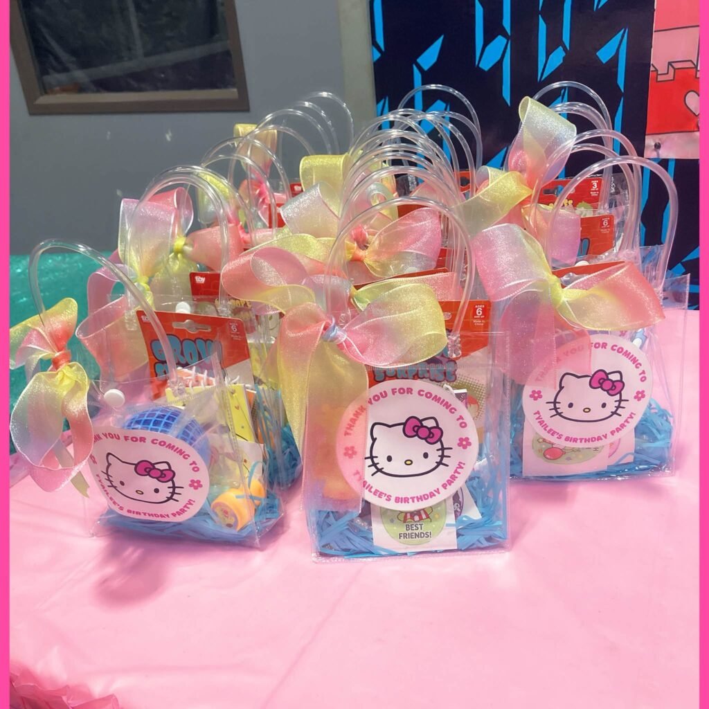 Clear favor bags with pastel ribbons and round Hello Kitty tags on a pink table