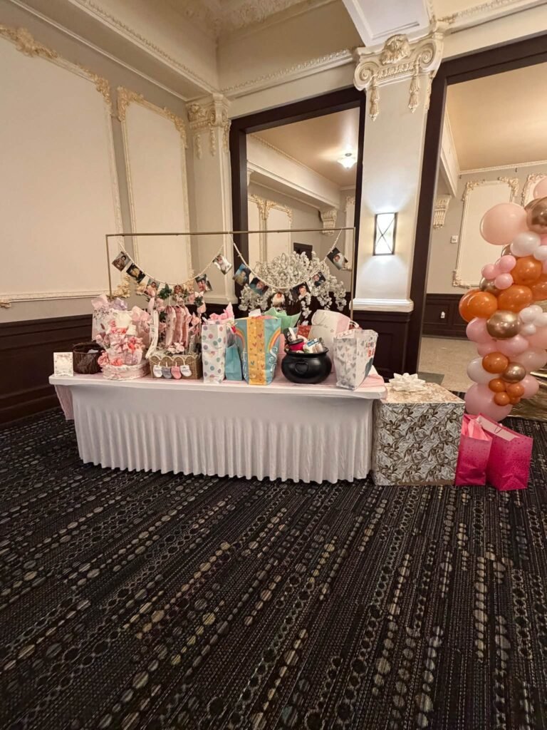 Pumpkin baby shower gift and treat table with a white skirt and balloons