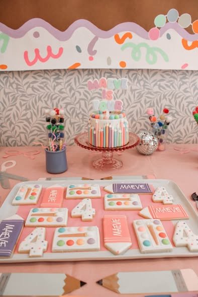 Arts and crafts birthday dessert table with paint palette cookies, number 4 cookies, crayon cookies and a striped cake