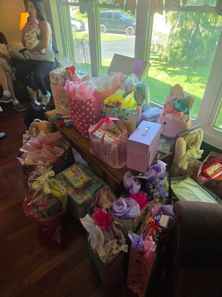 Pile of wrapped baby shower gifts and gift bags in a living room