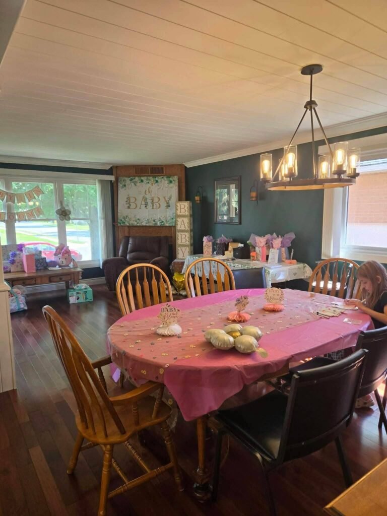 Dining room set for a baby shower with a pink tablecloth and small treats