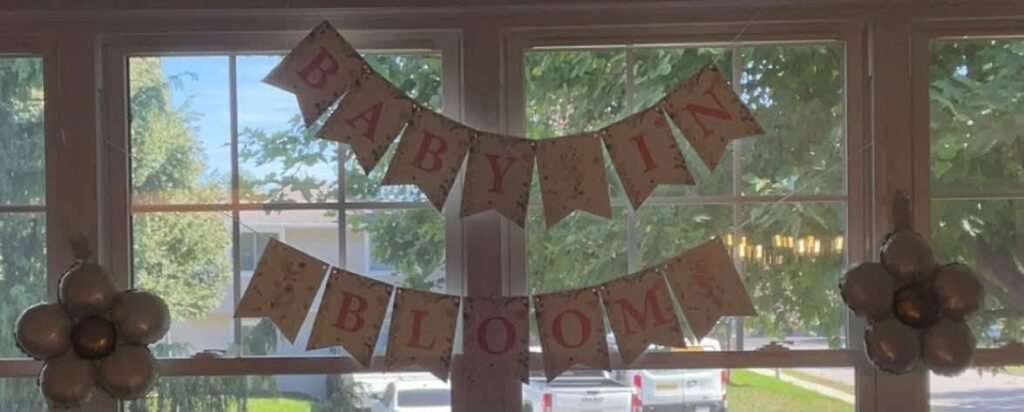 Burlap Baby in Bloom banner with fabric flowers hanging in a window