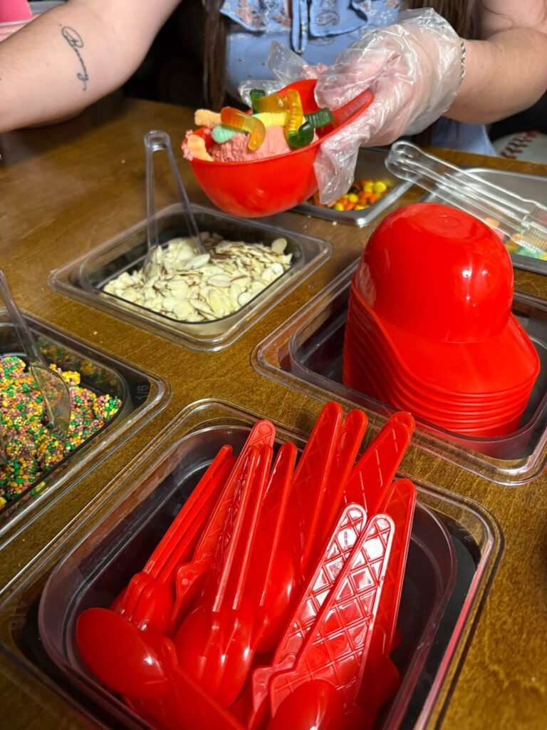 Mini red baseball helmets used as sundae bowls with red spoons and toppings