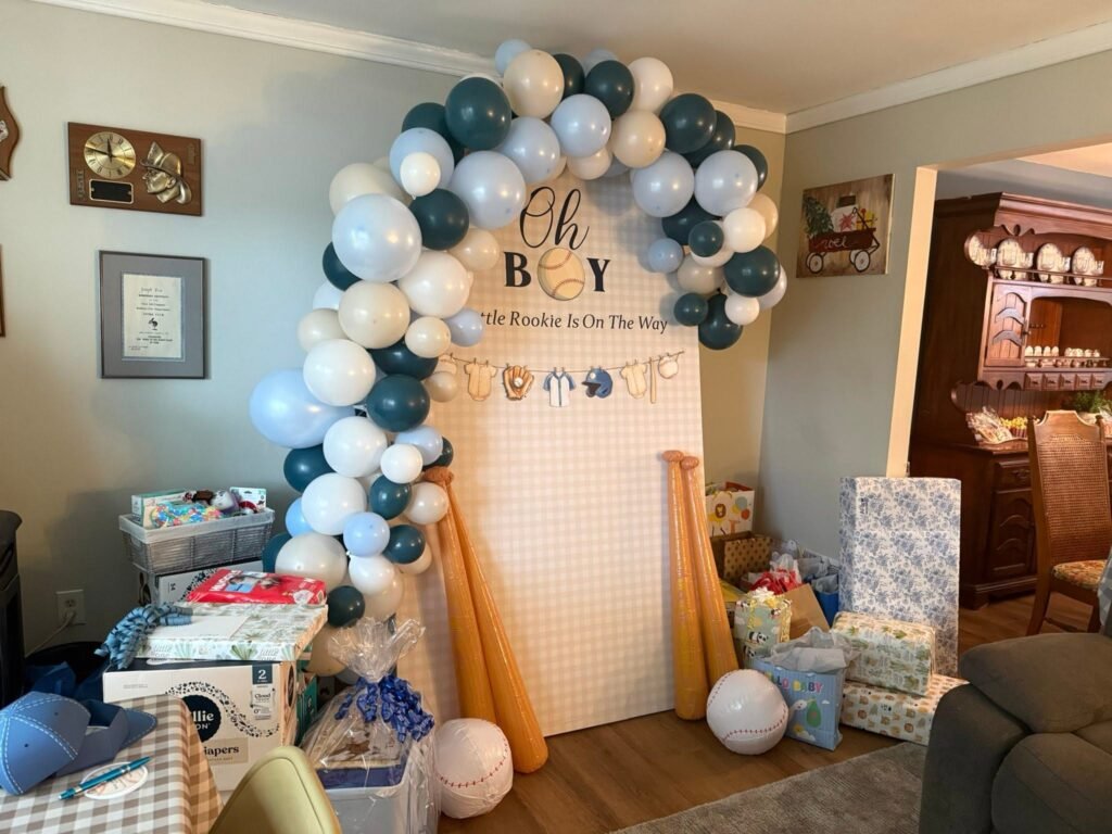 Oh Boy baseball baby shower balloon arch in navy, white and silver with a pegboard backdrop