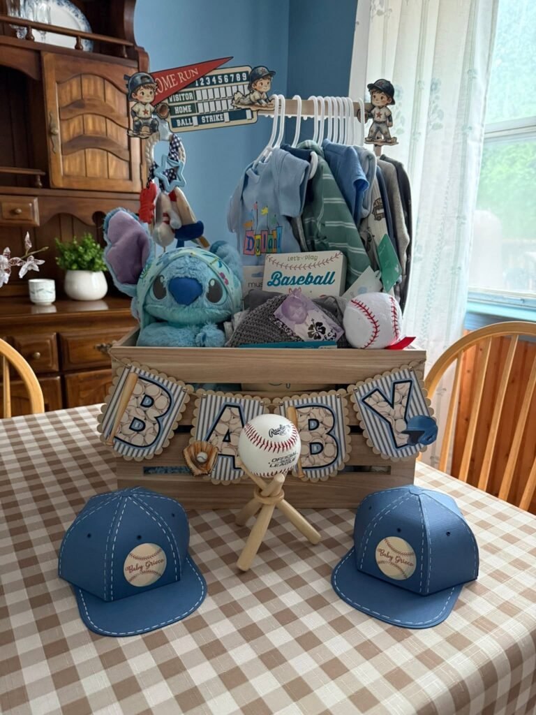 BABY crate centerpiece with baby clothes, a stuffed toy and baseball caps on a gingham table