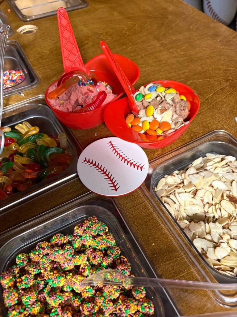 Baseball sundae topping bar with gummy candy, cereal, nuts and a baseball plate