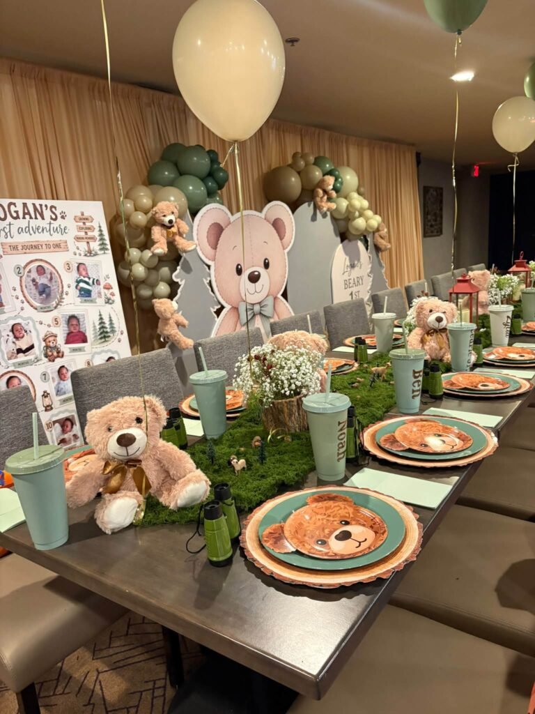 Woodland teddy bear 1st birthday party table with moss runner, bear plates and sage green balloons