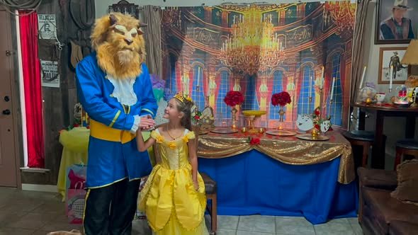 Beast character in costume with the birthday girl in a yellow Belle dress