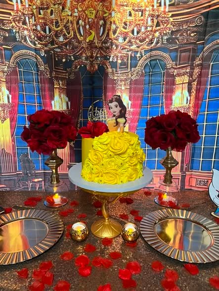 Yellow Belle birthday cake with ruffled rose frosting and a Belle topper between two vases of red roses