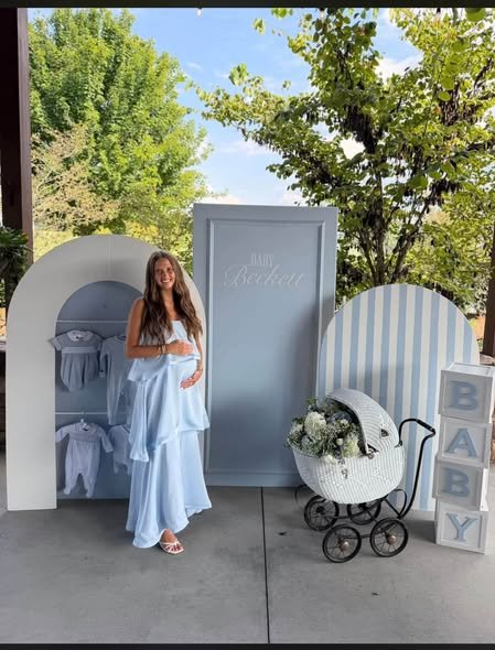 Mom to be in a light blue ruffle maxi dress by a blue striped backdrop