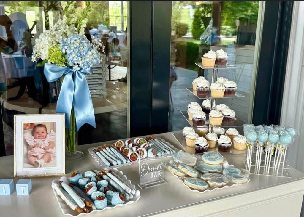 Blue and white baby shower dessert table with cupcakes, cake pops and a framed photo