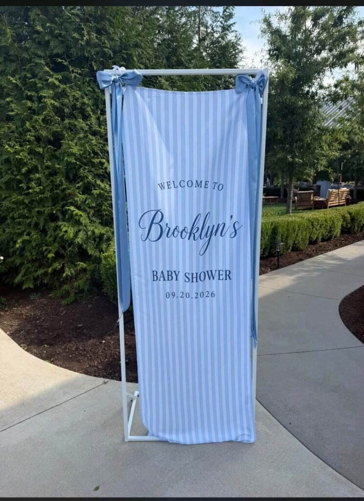 Blue and white striped baby shower welcome sign on a stand outdoors