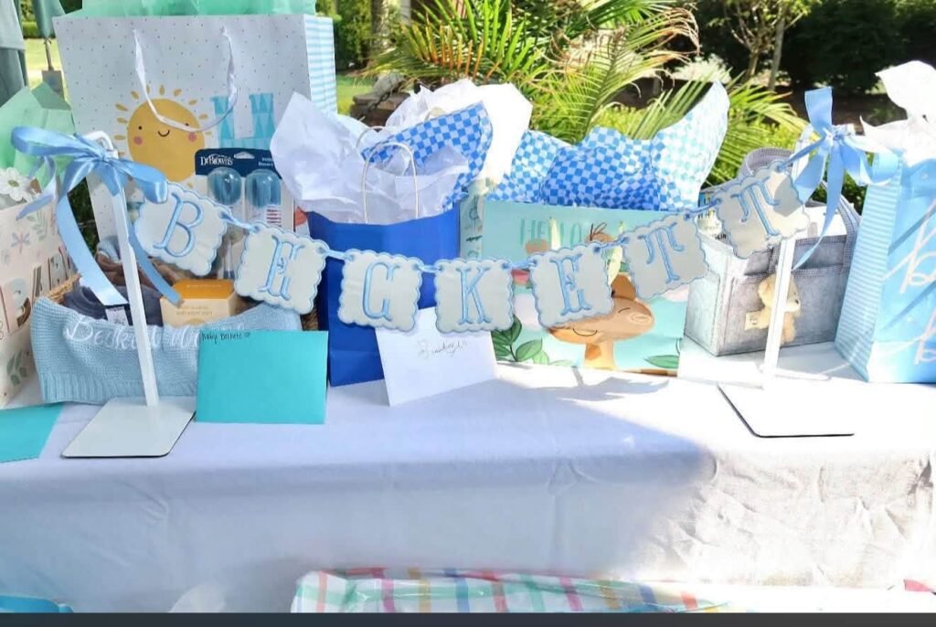 Blue and white baby shower table with a banner and wrapped gifts