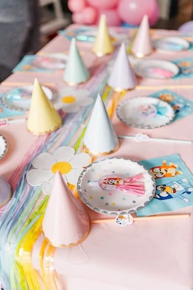 Pink Bluey party table with pastel party hats, daisy plates and Bluey napkins