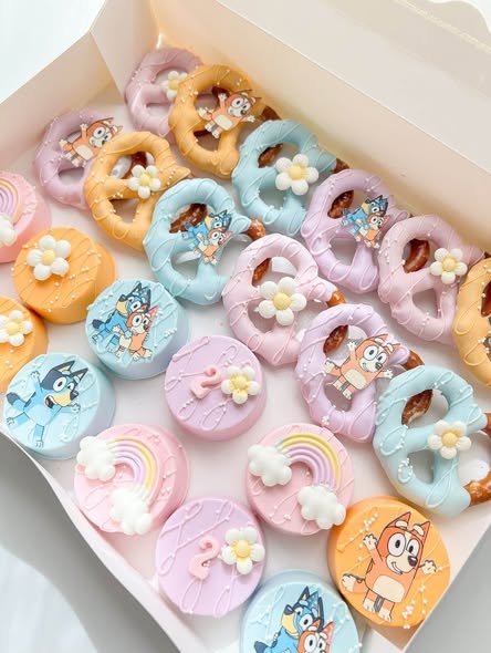 Chocolate dipped Oreos and pretzels in pastel colors with Bluey, Bingo, daisy and rainbow toppers