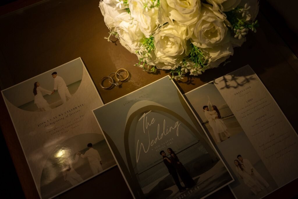 Wedding invitation flat lay with wedding rings and white roses