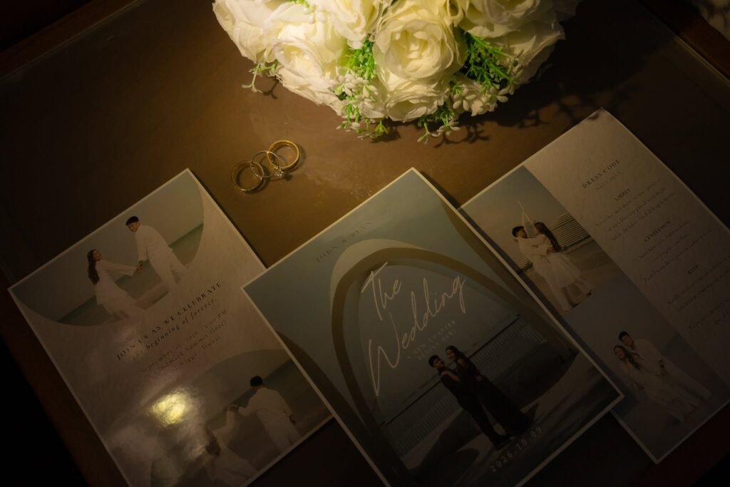 Wedding invitation suite and rings under a white rose bouquet