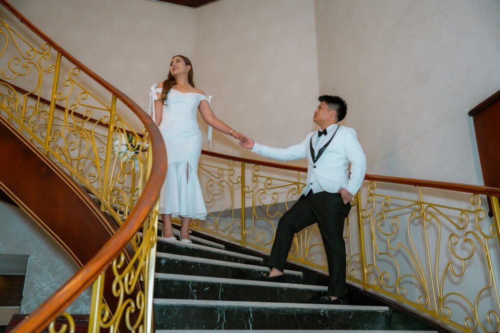 Bride and groom holding hands on a curved gold staircase