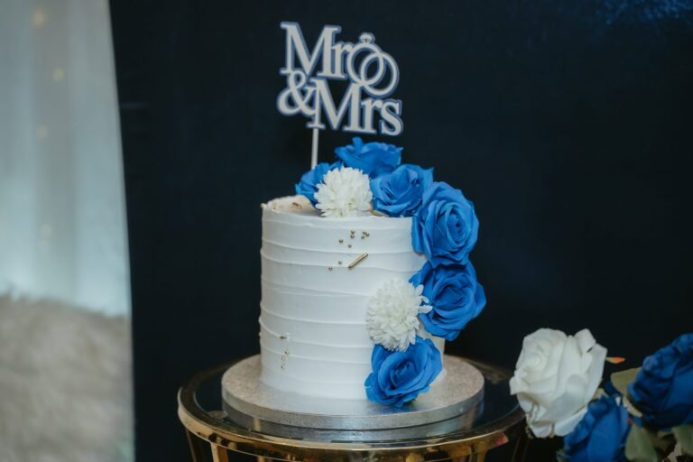 One tier white wedding cake with royal blue roses and a silver Mr and Mrs topper