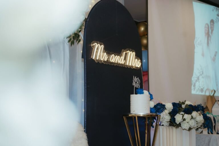 Navy arch with a warm Mr and Mrs neon sign next to a blue and white flower stand
