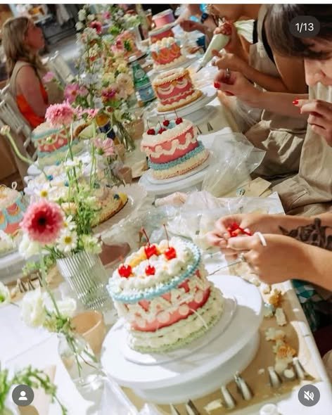 Picnic table full of decorated cakes with fresh flowers in glass vases