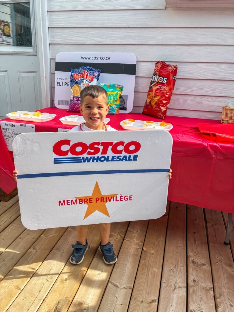 Kid holding a Costco Wholesale membership sign at a Costco themed birthday party