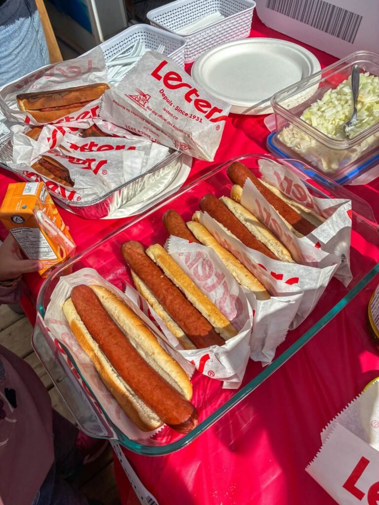 Hot dogs in paper wrappers on a red party table for a Costco theme