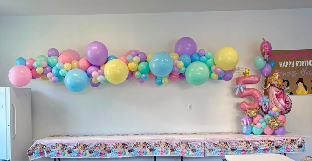 Pastel balloon garland with princess foil balloons over a long party table