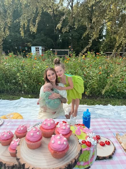 Two girls hugging at a fairy garden picnic with pink cupcakes on wood slices
