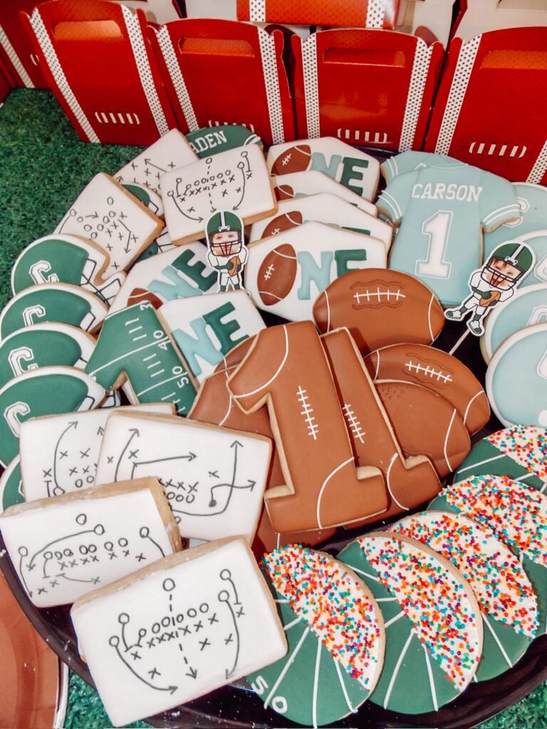Football party sugar cookies shaped like jerseys, footballs, number 1 and play diagrams