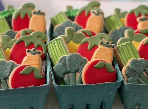 Veggie sugar cookies shaped like tomatoes, carrots, broccoli and celery packed in green berry baskets