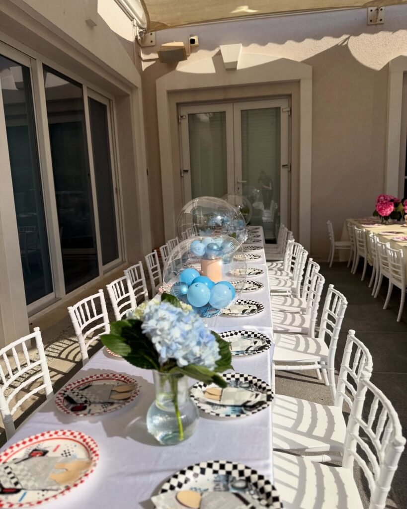 Race car party table with checkered plates, blue hydrangeas and clear bubble balloons filled with blue balloons
