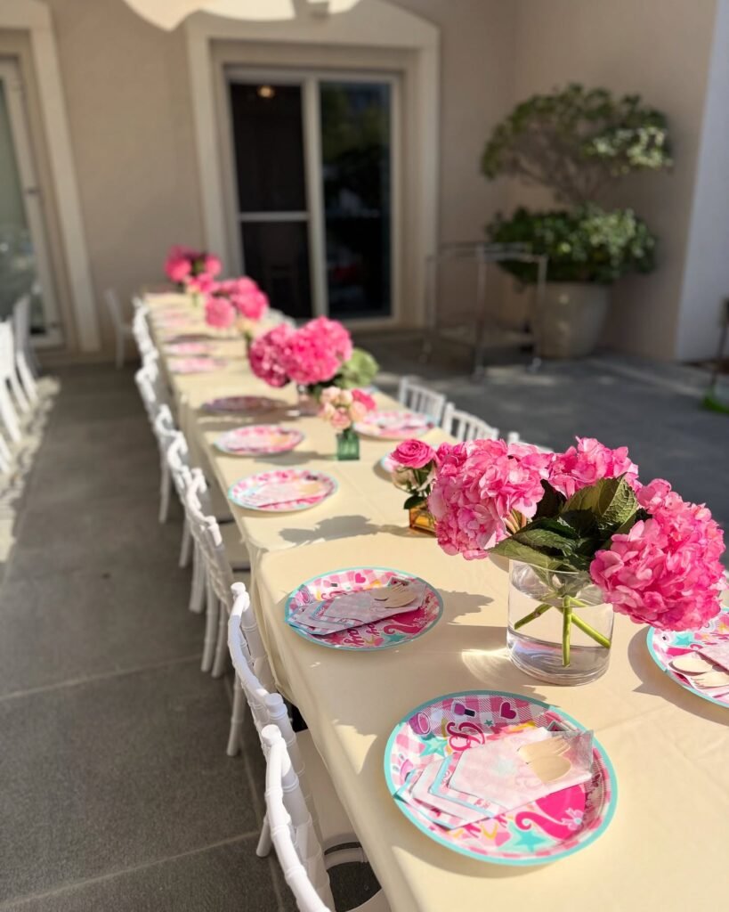 Pink Barbie party table with pink plates, napkins and big bunches of pink hydrangeas in glass vases