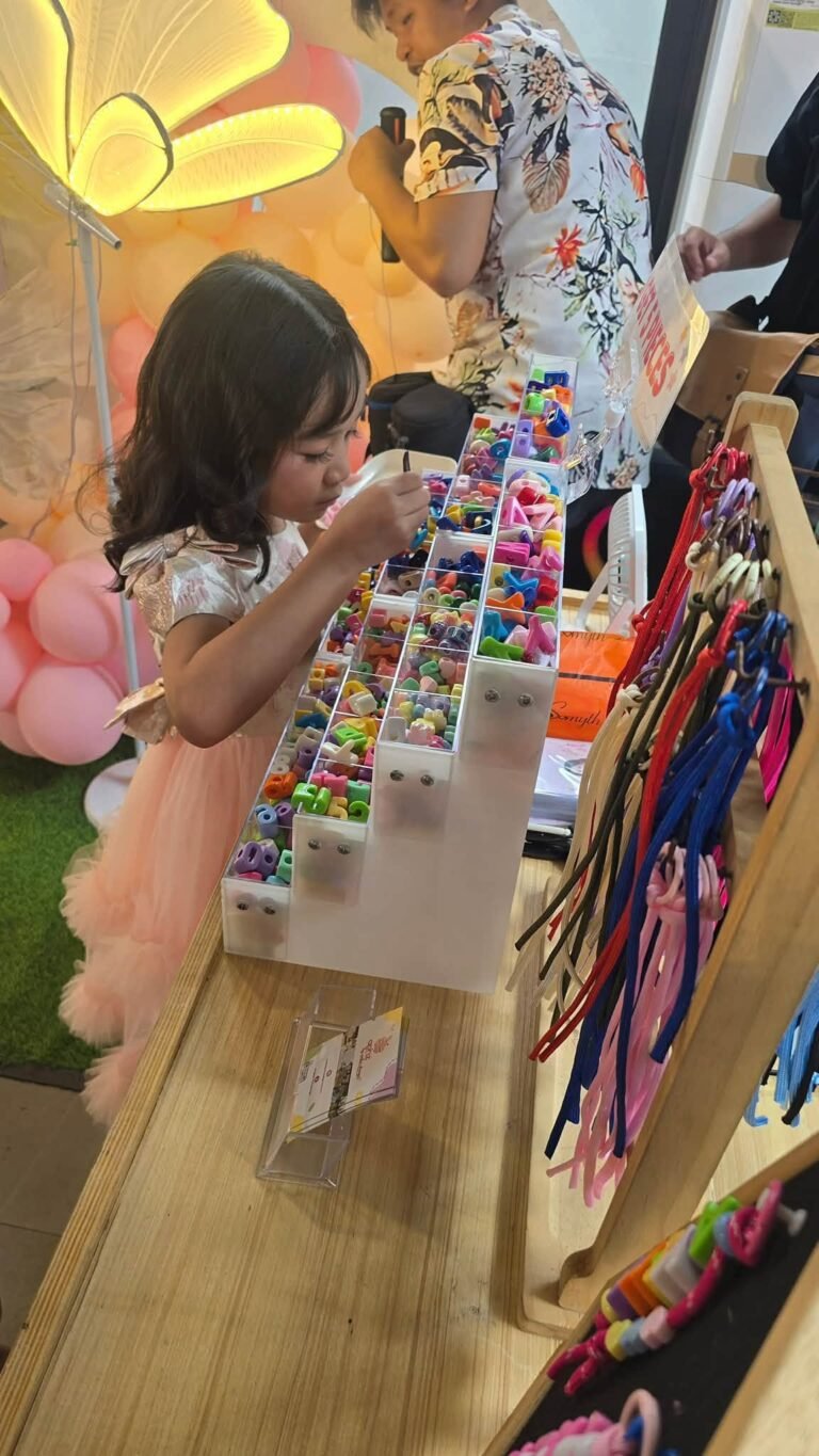 Girl in a pink dress choosing charms at a birthday party souvenir booth