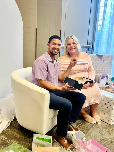 Parents to be on a white chair opening gifts at a Heaven Sent baby shower