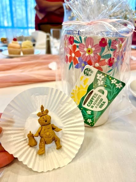 Baby shower favor with a floral tumbler, a coffee gift card and a treat on a pink table