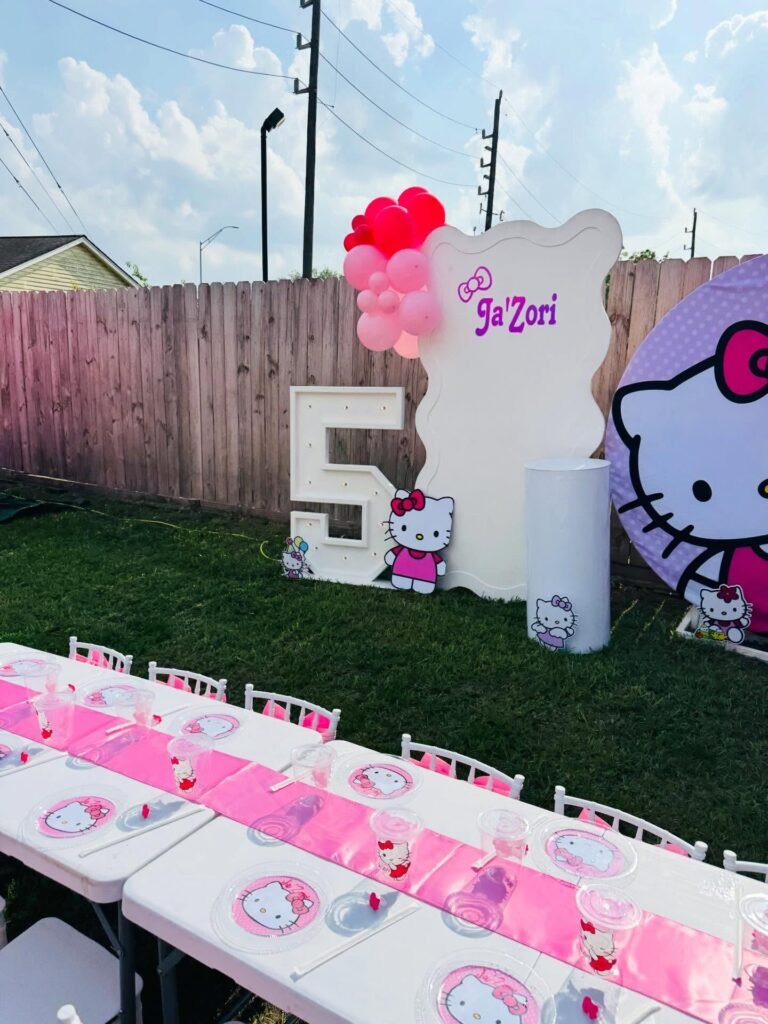 Marquee number 5 next to a wavy white name panel with a pink bow and a Hello Kitty cutout on a lawn