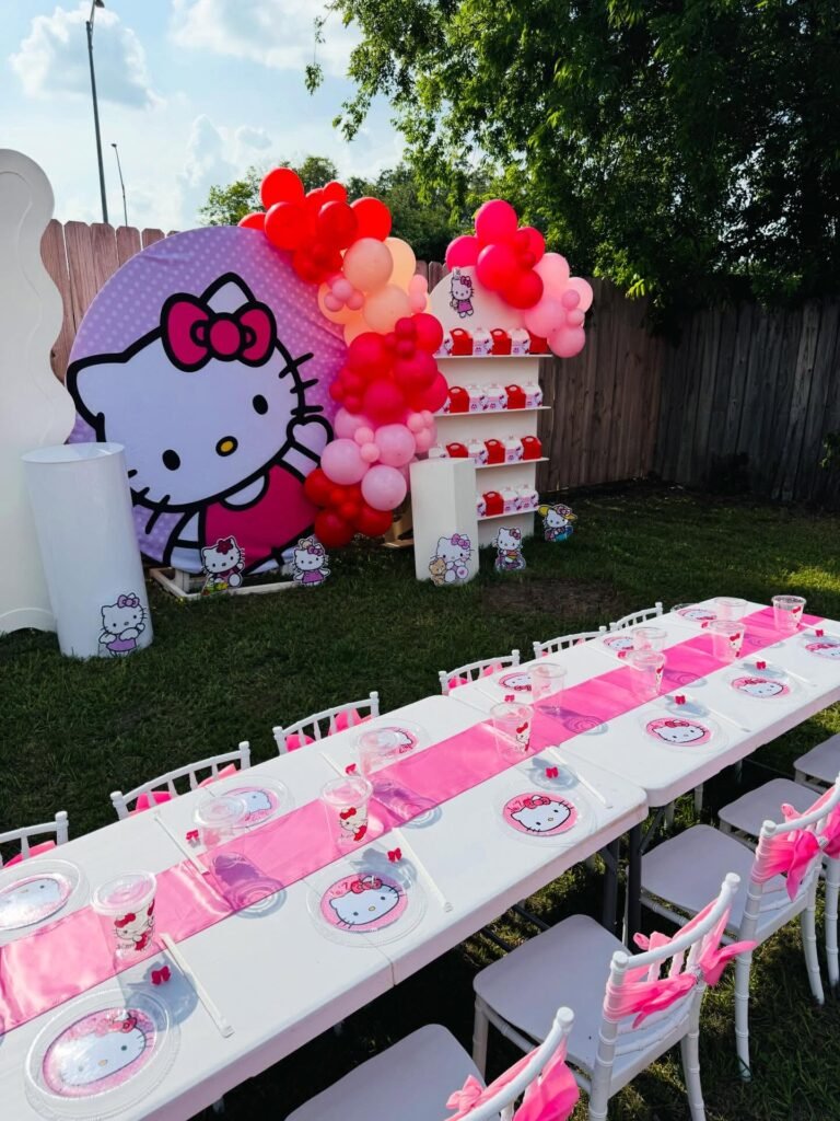 Backyard Hello Kitty 5th birthday with a big Hello Kitty cutout, balloons and long pink tables