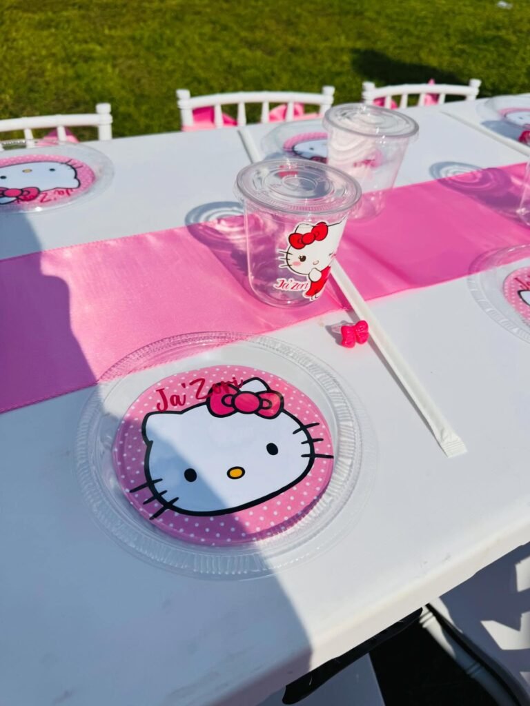 Hello Kitty place setting with a pink Hello Kitty plate, a clear cup and a pink table runner on a white table