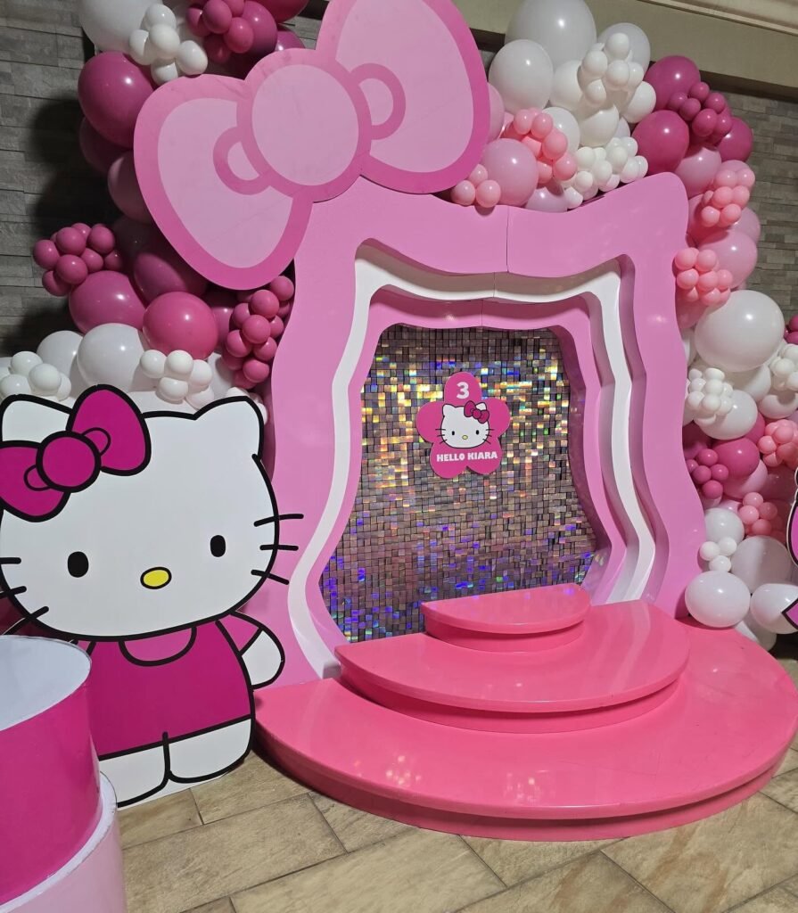 Pink Hello Kitty bow throne backdrop with balloons and a sequin wall