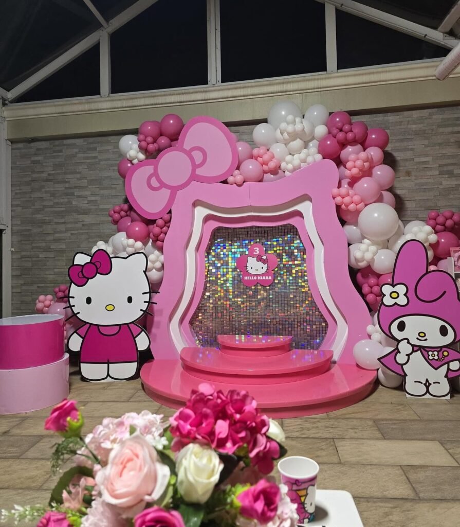 Hello Kitty head frame with a big pink bow around a shimmer wall, with balloon garlands and character cutouts