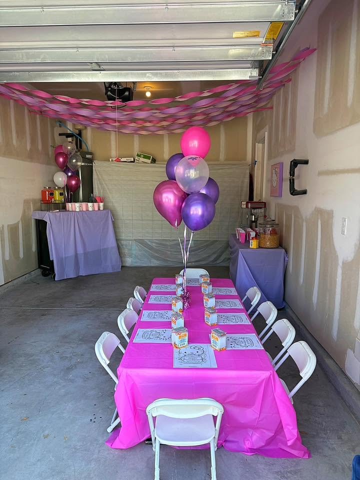 Long view of a Hello Kitty garage party with balloons and a pink kids table