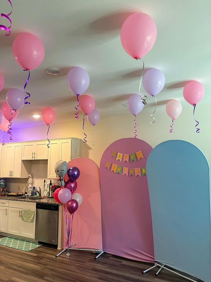 DIY Hello Kitty birthday backdrop with pink and blue arch panels, a Happy Birthday banner and pink and lilac balloons