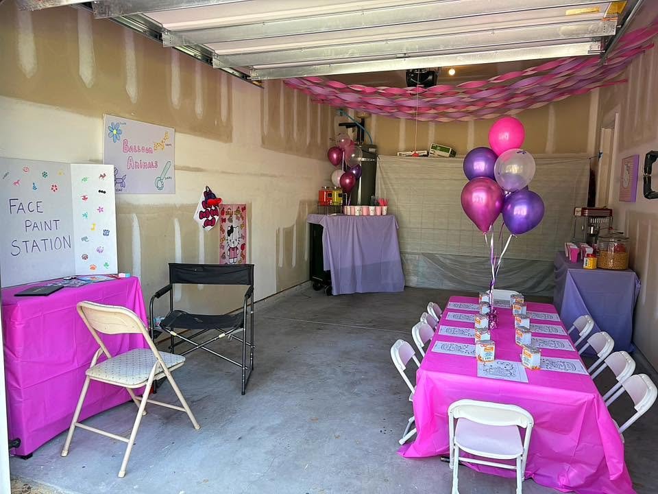 Garage set up for a Hello Kitty party with a pink table, streamers and white chairs