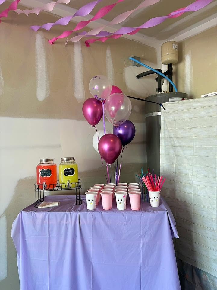 Lavender drink table with a balloon bunch, drink dispenser and pink cups